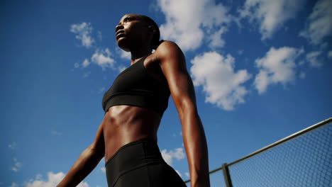 woman in athletic wear stretching outdoors under a blue sky