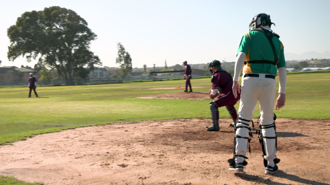 Playing baseball, catcher walking towards home plate during game on sunny day