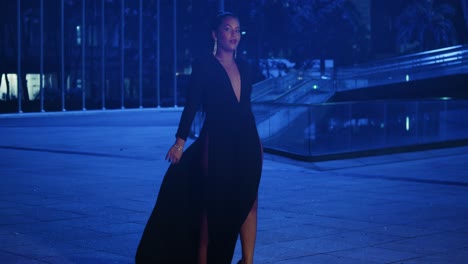 Young-woman-walking-in-a-black-dress-at-night-in-the-Caribbean-city-of-Port-of-Spain,-Trinidad