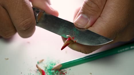 Footage-of-hands-slowly-sharpening-a-pencil-and-some-coloured-pencils-with-a-sharp-knife