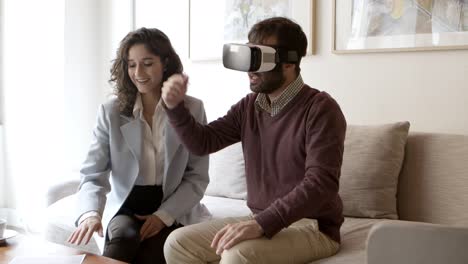 bearded young man gesturing while using vr headset at home