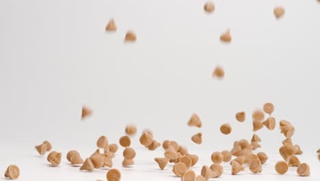 Butterscotch-baking-chips-landing-on-white-table-top-in-slow-motion