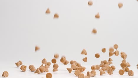 chips de caramelo para hornear aterrizando en la parte superior de la mesa blanca en cámara lenta