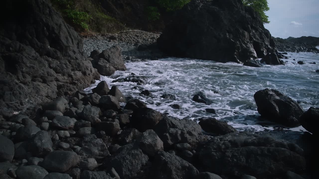 코스타리카의 바위 해변 위로 파도가 움직입니다.