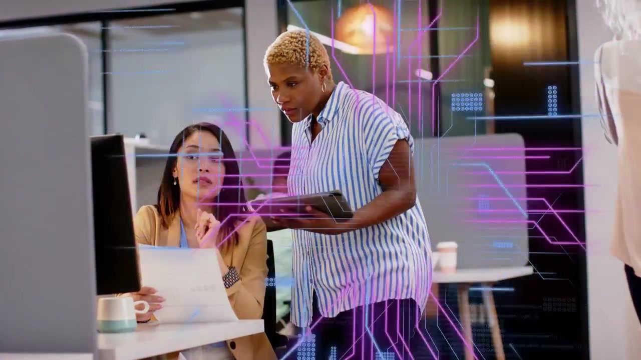 Designer pointing at screen and paper peer leaning with tablet HUD linking screens checking data