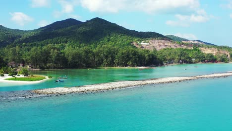 unspoiled turquoise lagoon with a sandbank, sand beach and hilled jungle in the background