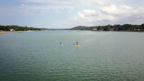 a drone shot moving forward toward women doing stand up paddle on a lake in hossegor, south of france