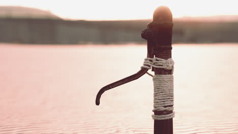 Rusty-old-metal-water-pump-on-sand-beach