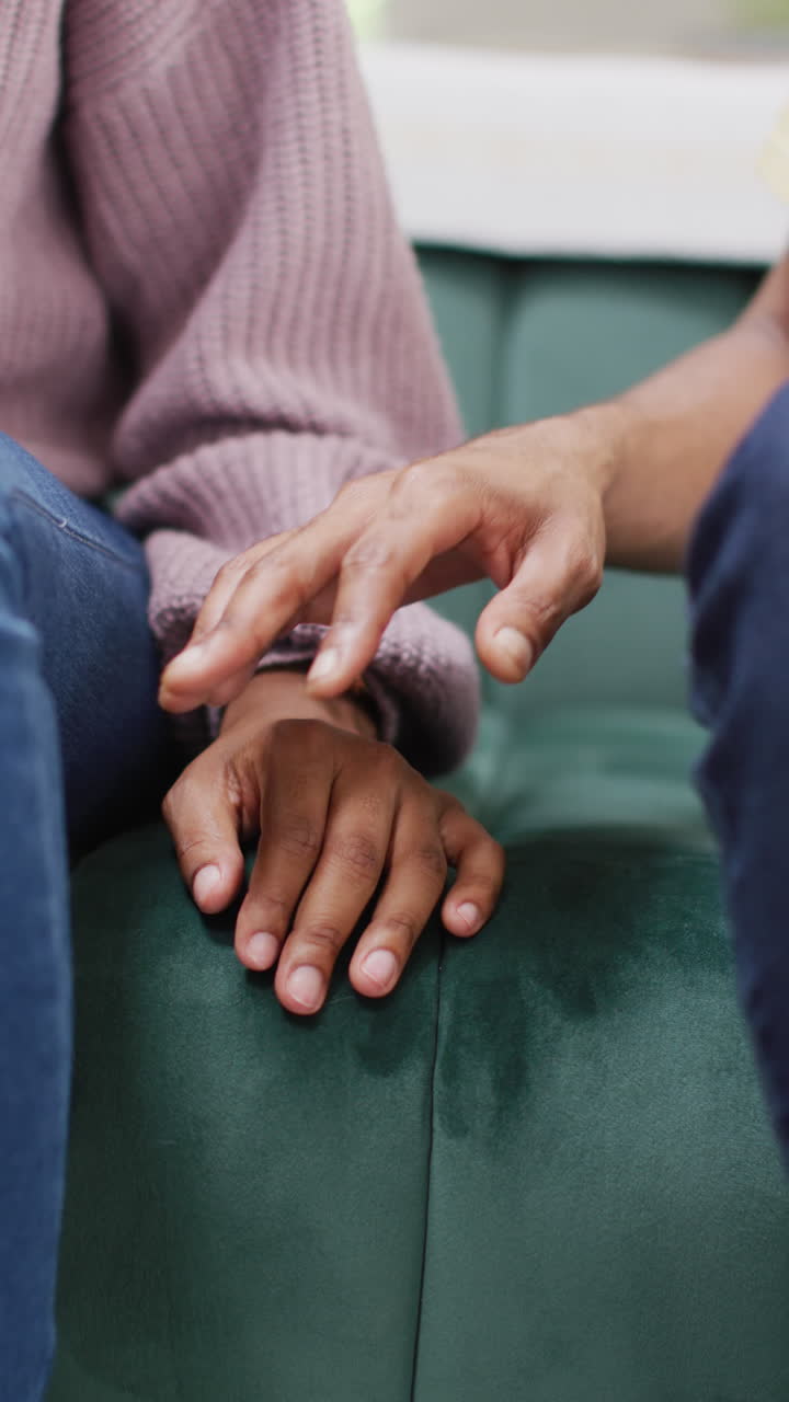 Vertical video of hands of african american couple touching