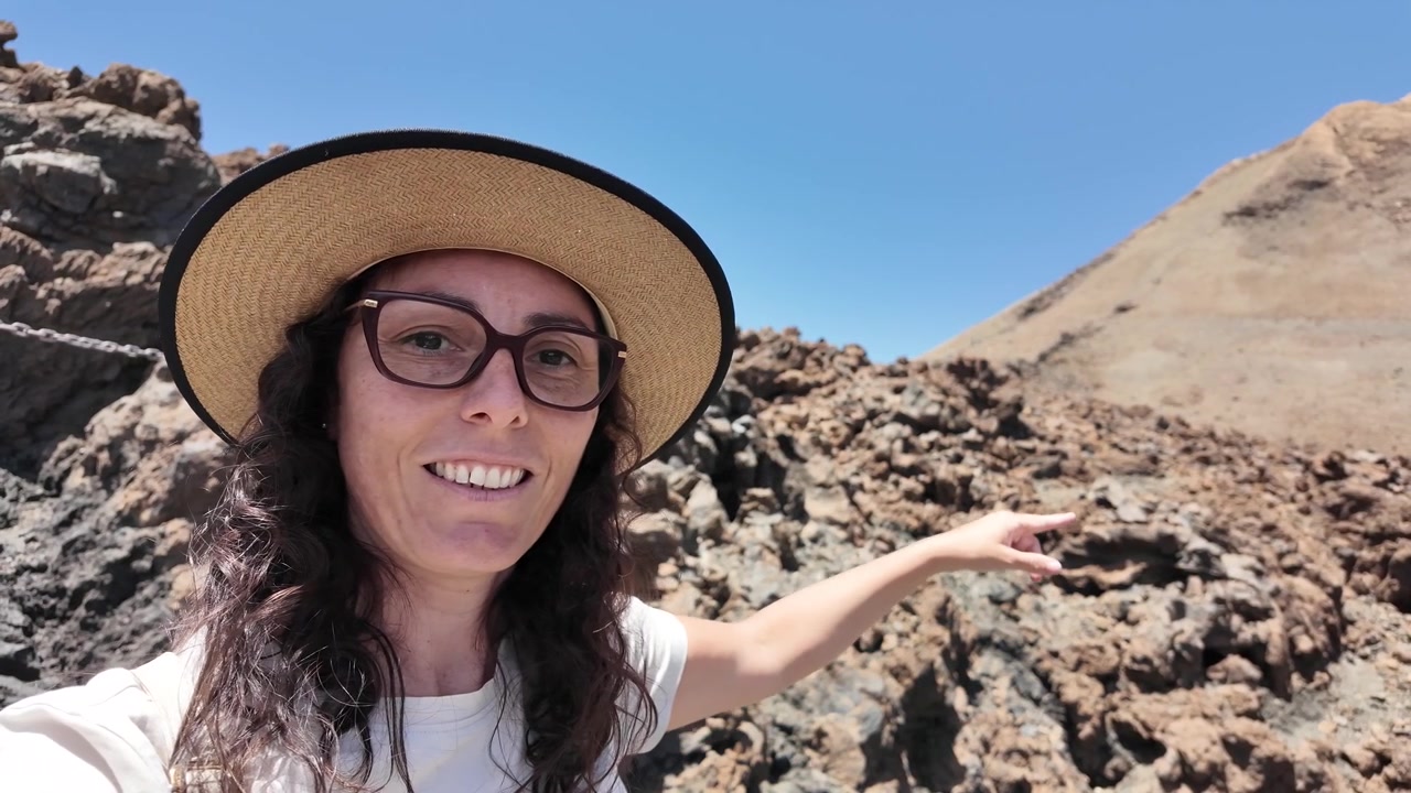 Donna con cappello che indica un paesaggio montano vulcanico