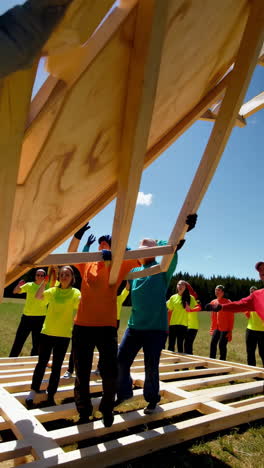 volunteers building a wooden structure together outdoors on a sunny day