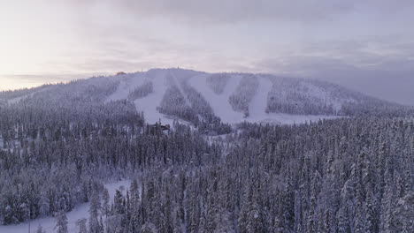 Drone-shot-approaching-the-slopes-of-Iso-Syote,-winter-sunrise-in-Finland