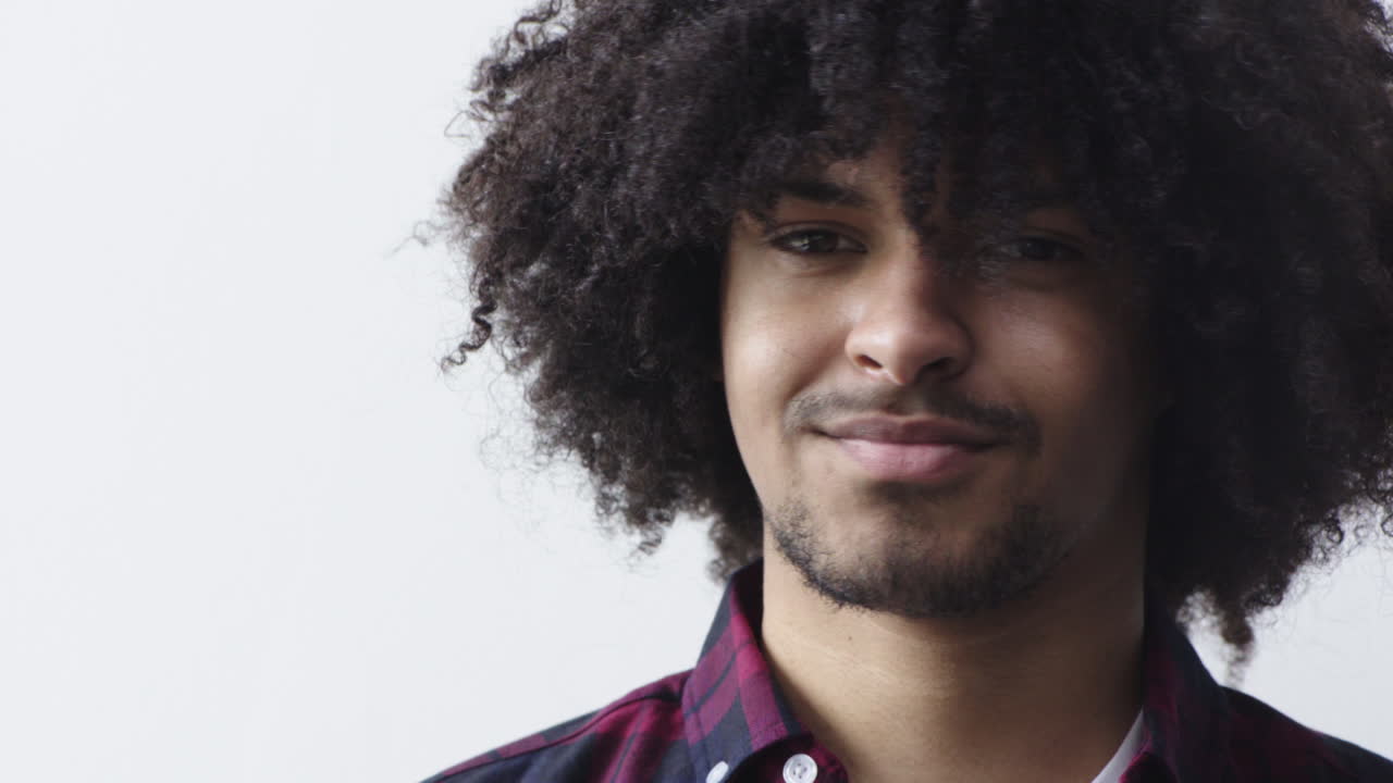 ritratto ravvicinato di un giovane uomo di razza mista che sorride felice gira la testa guardando la telecamera studente maschio di successo con capelli afro alla moda su sfondo bianco