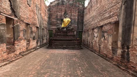 buddha statue draped in yellow cloth among ancient ruins