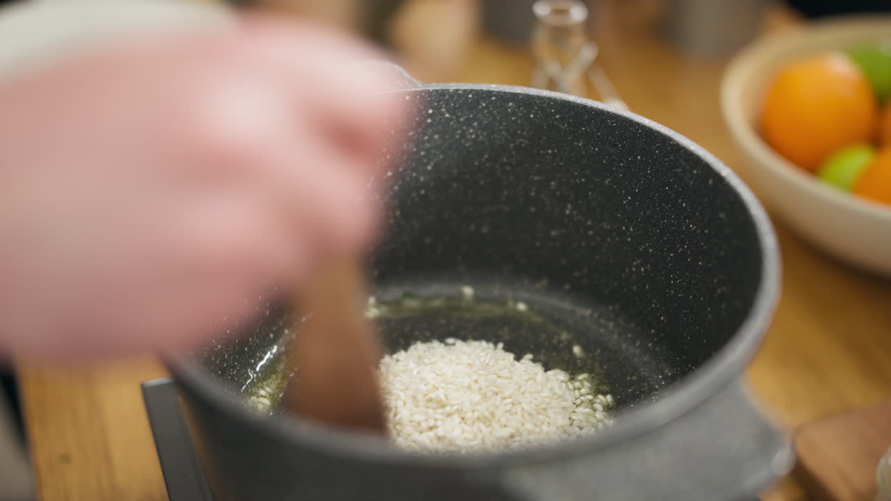 Close up shot of hands putting raw risotto into a saucepan, interior