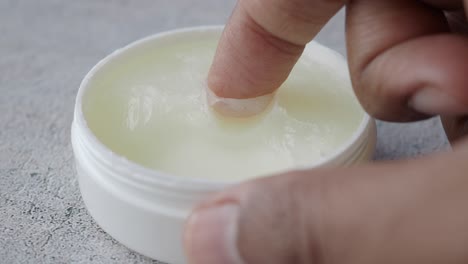 closeup of a hand applying cream from a jar