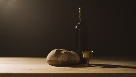 religious concept shot with chalice bread and wine on wooden altar with pool of light