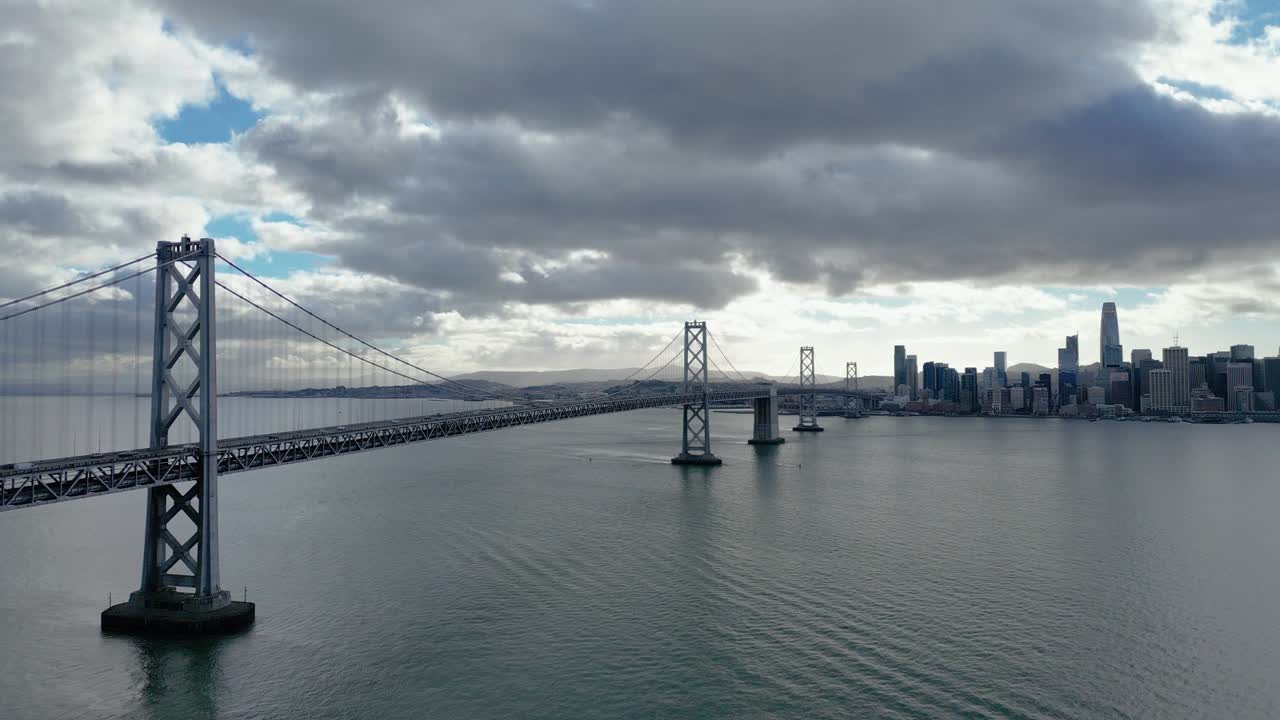 A horizontal side-tracking drone shot of The Bay Bridge from Yerba Buena Island, CA, capturing the bridge and surrounding bay. Perfect for urban, architectural, and coastal footage.