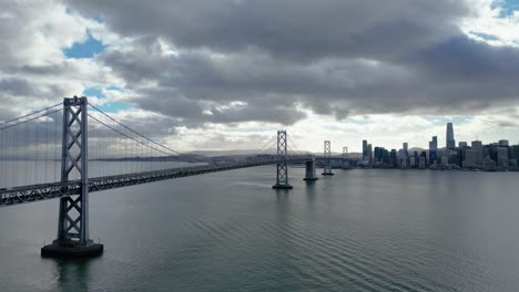 a horizontal side-tracking drone shot of the bay bridge from yerba buena island, ca, capturing the bridge and surrounding bay. perfect for urban, architectural, and coastal footage.
