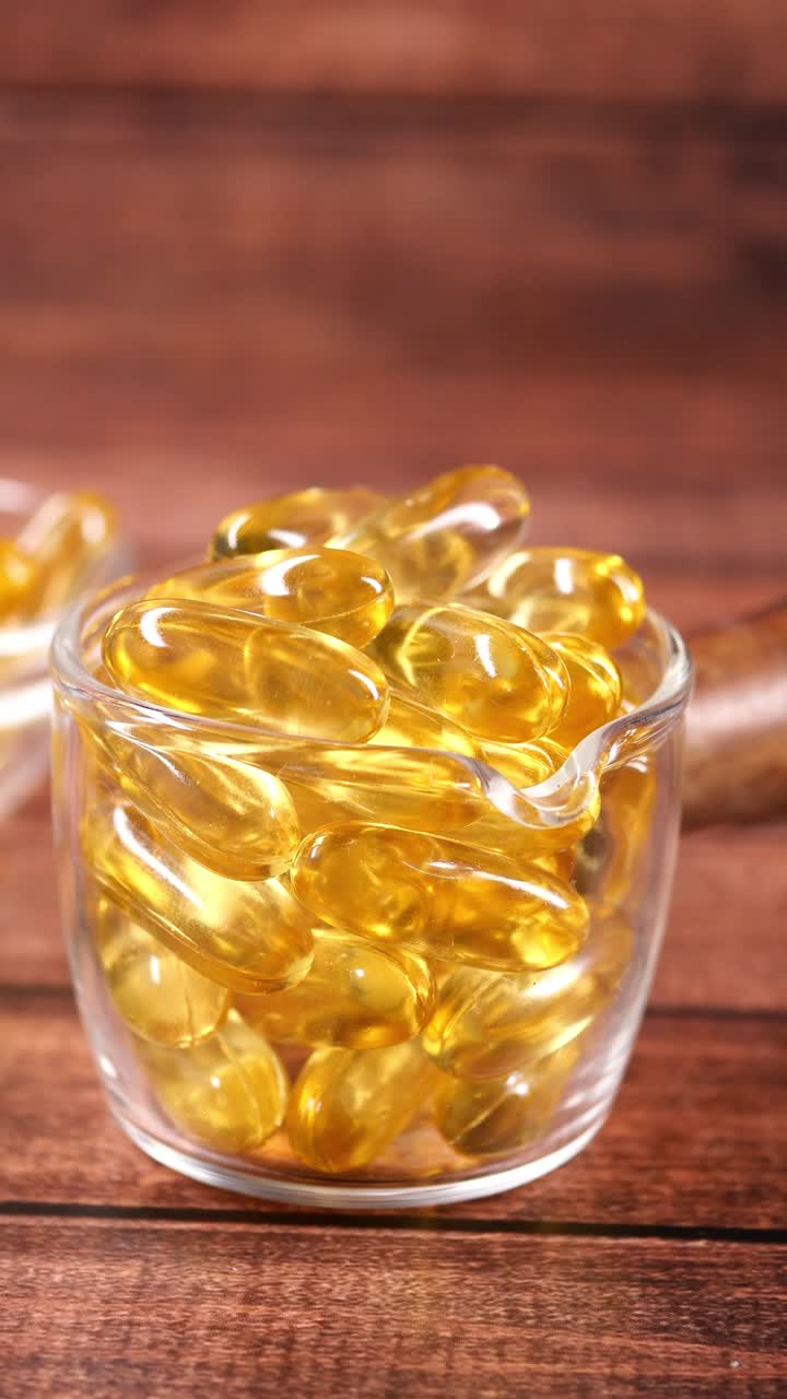 Primo piano di capsule gialle di olio di pesce Omega 3 in un contenitore di vetro.