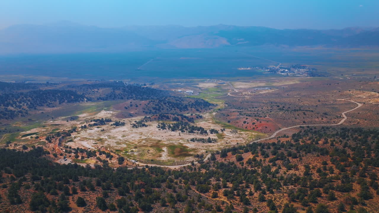 Beautiful scenery of unusual landscape of Travertine Hot Springs in California, USA. Mountains in deep blue fog at backdrop. Aerial view.