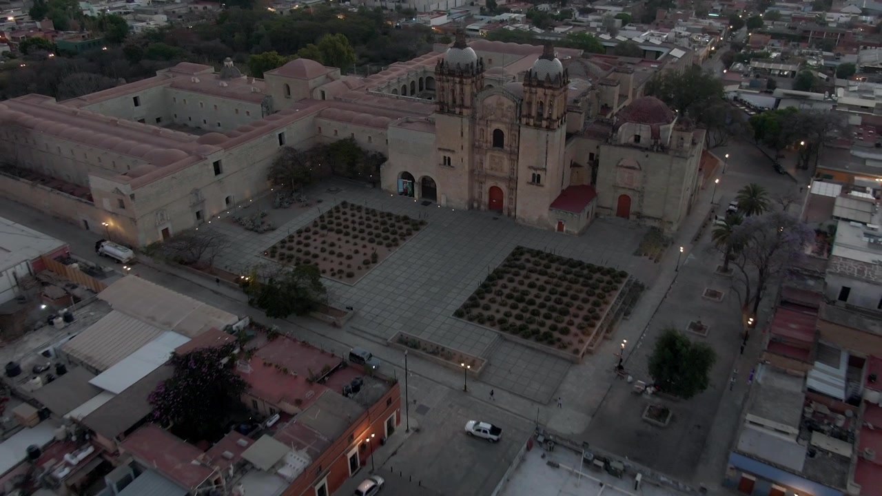 Vista aerea con drone della Chiesa di Santo Domingo de Guzmán e del centro storico circostante, illuminati dalla luce soffusa della sera a Oaxaca City, Messico, al tramonto