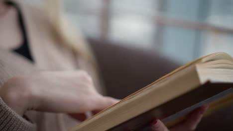 close-up of hand turning a page in a book with slight blur, focusing on the motion of the hand as it flips over to the next page while the book remains partially out of focus