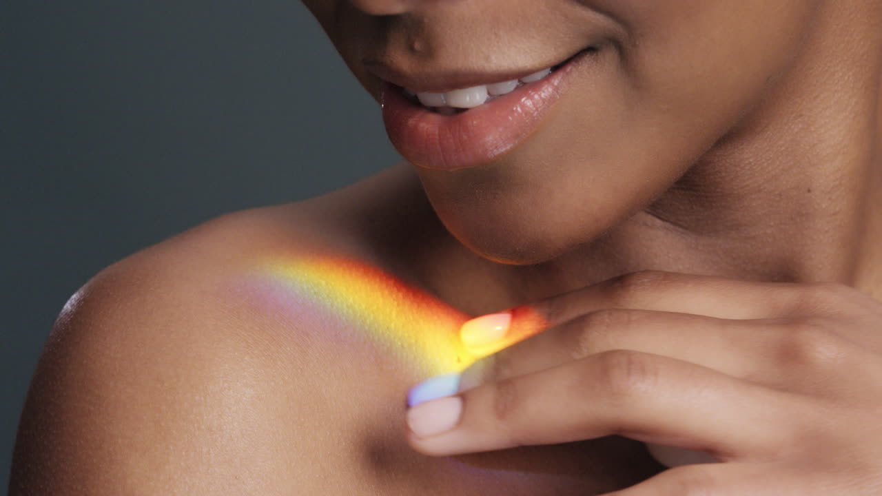 ritratto multicolore ravvicinato bella donna afroamericana che tocca le spalle accarezza la pelle nuda godendo della cura della pelle bellezza con luce colorata che si riflette sulla carnagione liscia