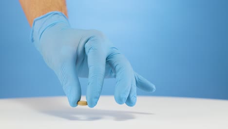 doctor with blue gloves places a vegan vitamin b12 supplement on white surface