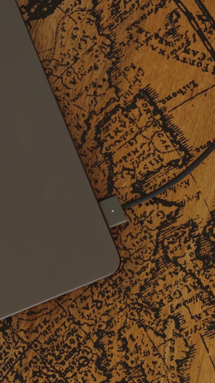 Primo piano di una mano che inserisce un cavo di ricarica in un portatile per ricaricare la batteria, a rappresentare la tecnologia portatile e l'alimentazione elettrica