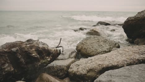 el agua de mar hace espuma y las olas se estrellan contra las rocas durante el día