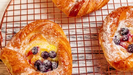 delicious fresh baked cheese danish pastries with powder sugar and blueberries on cooper cooling rack, close up top view