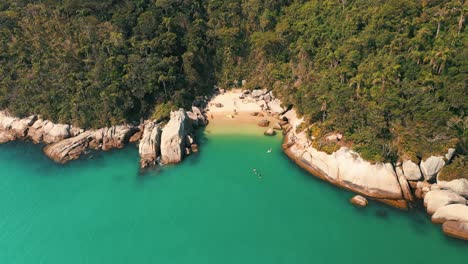 Vista-Aérea-Acercándose-A-Una-Playa-Paradisíaca-Secreta-Brasileña-Con-Agua-De-Color-Turquesa-Ubicada-En-Bombinhas,-Santa-Catarina,-Brasil