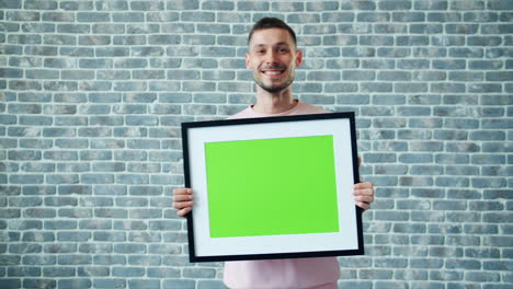 man holding a picture frame with a green screen