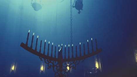 candle lit chandelier hanging in a dimly lit ancient cave setting