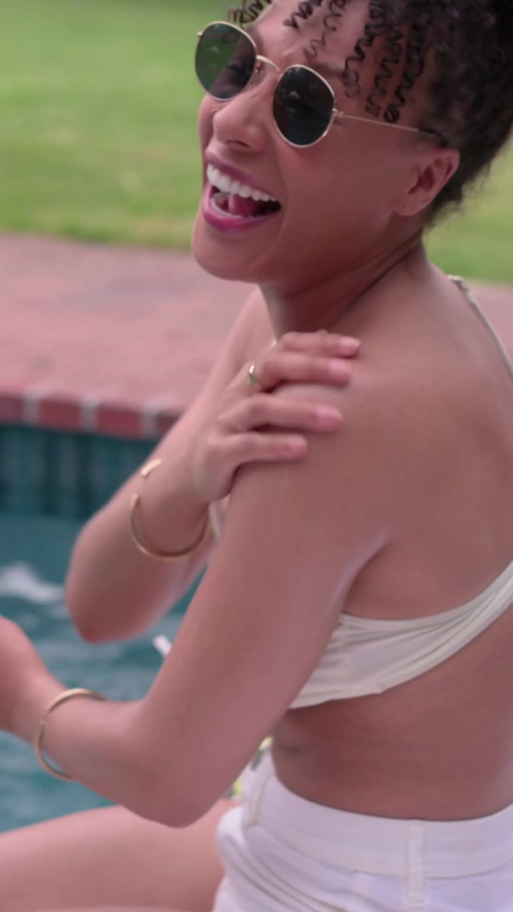 Vertical video: Feeling warm sun, woman in white bikini applying sunscreen to shoulder at poolside