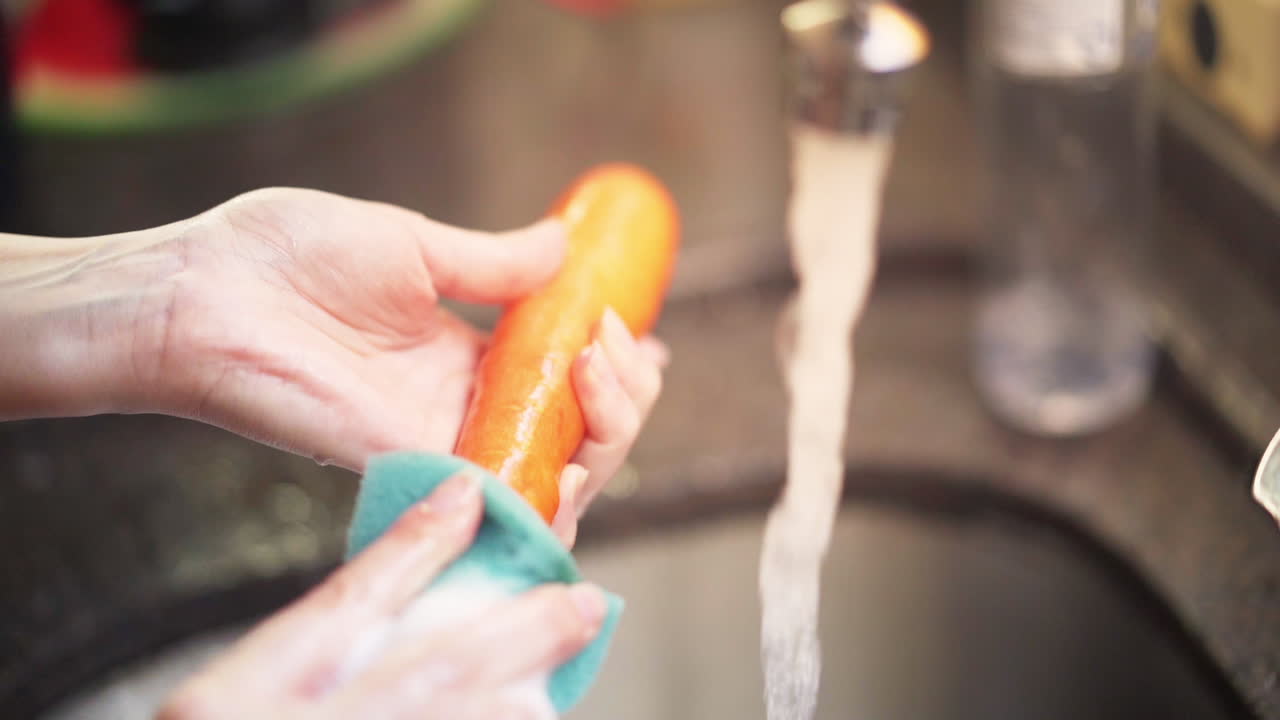 Washing a carrot in the kitchen in slow motion