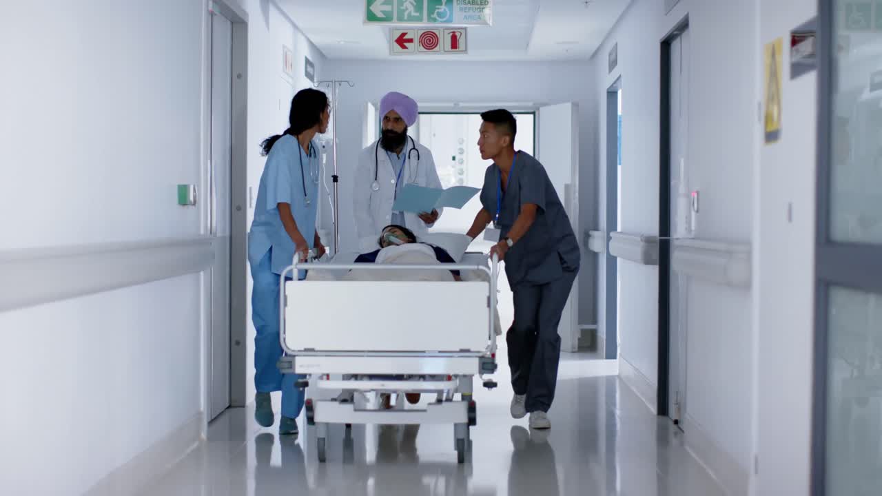 Medici e chirurghi di diverse etnie indaffarati che camminano con un paziente su un letto d'ospedale, al rallentatore.