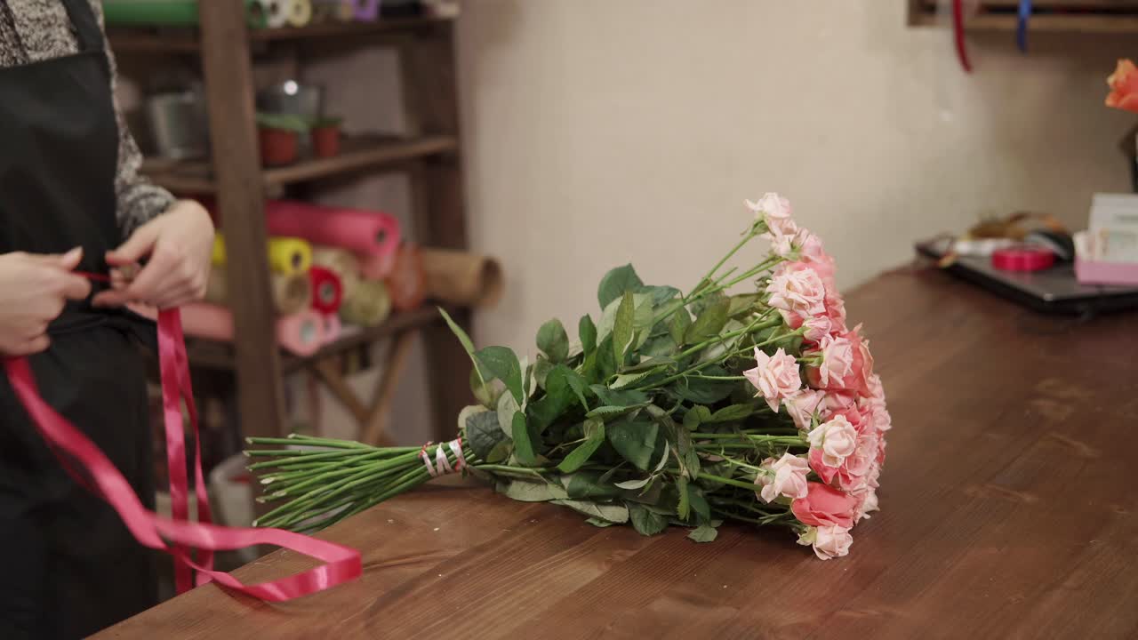 florista arreglando un ramo de rosas rosas