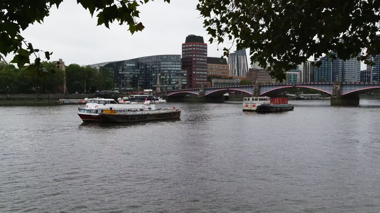 View of boat houses on London Thames with Lambeth Bridge and apartment buildings in the background.