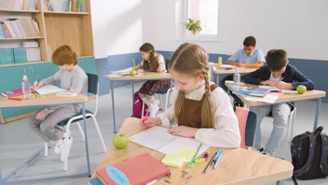 multiethnic group of kids in classroom writing in their notebook and smiling during english class at school 1