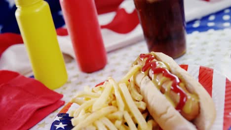perrito caliente, papas fritas y bebida fría servida en una mesa con tema del 4 de julio