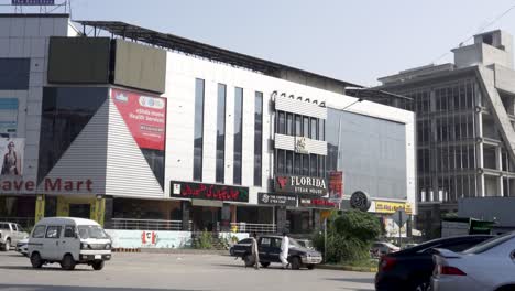 a remarkable commercial building looms tall on the main road, surrounded by parked cars in the front.