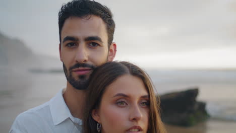 Handsome-man-looking-camera-misty-beach-portrait.-Loving-couple-cuddling-ocean