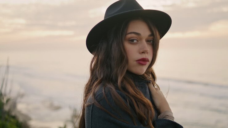 Donna sognante che posa sulla costa in una giornata nuvolosa, primo piano. Ritratto di attraente ragazza bruna.
