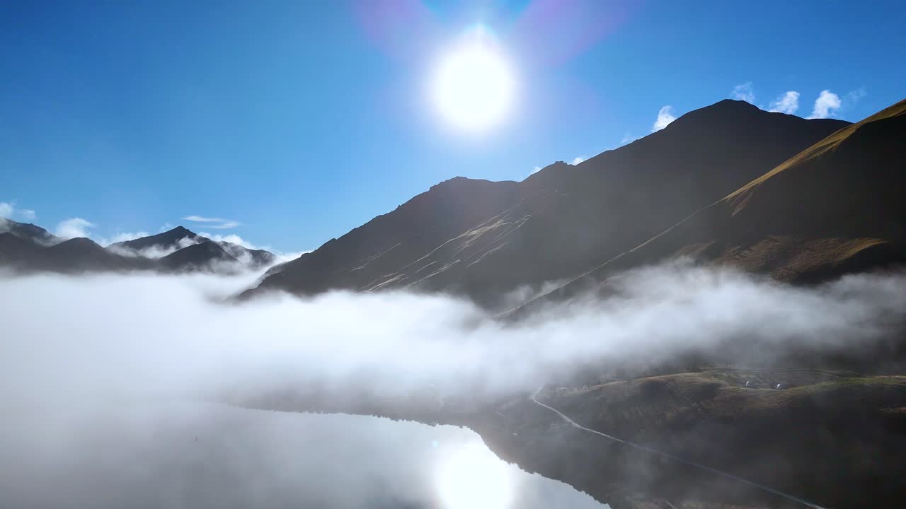 Sunrise illuminates fog rolling over Moke Lake, creating a serene and ethereal landscape in Queenstown, New Zealand