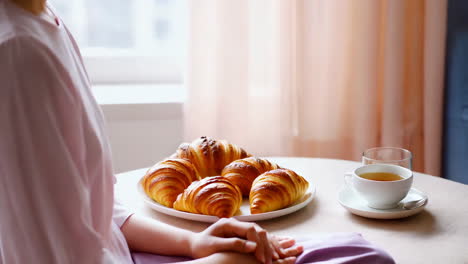 person enjoying breakfast with croissants and tea