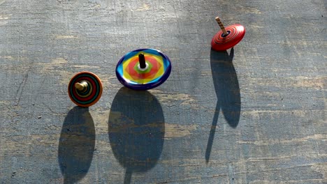 three colorful top spin whirligigs rotating on ooden background
