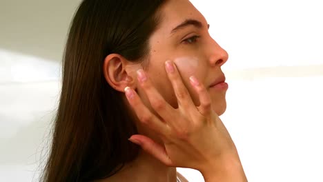 mujer joven aplicando crema en su cara