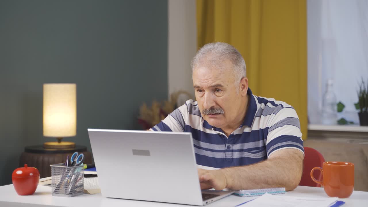 Home office worker old man working on laptop stressed.
